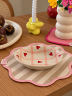 A ceramic bowl with a pink plaid pattern and red hearts.