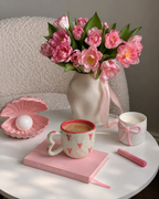 a white mug with pink heart patterns and a heart-shaped handle
