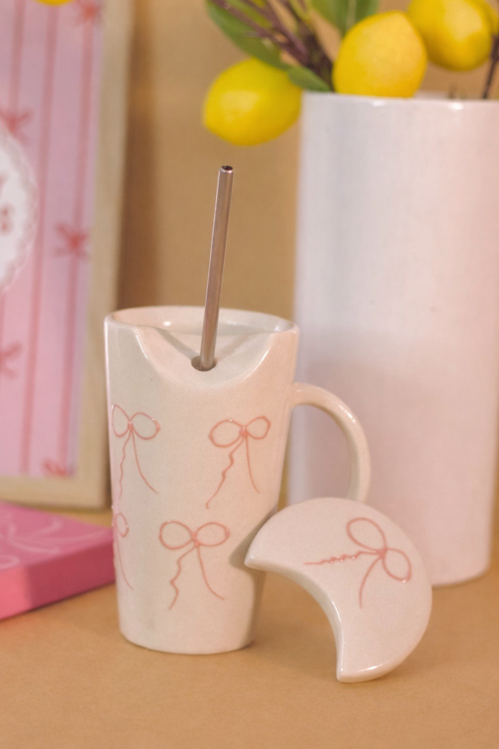 White ceramic cup with bow design, straw, and matching coaster
