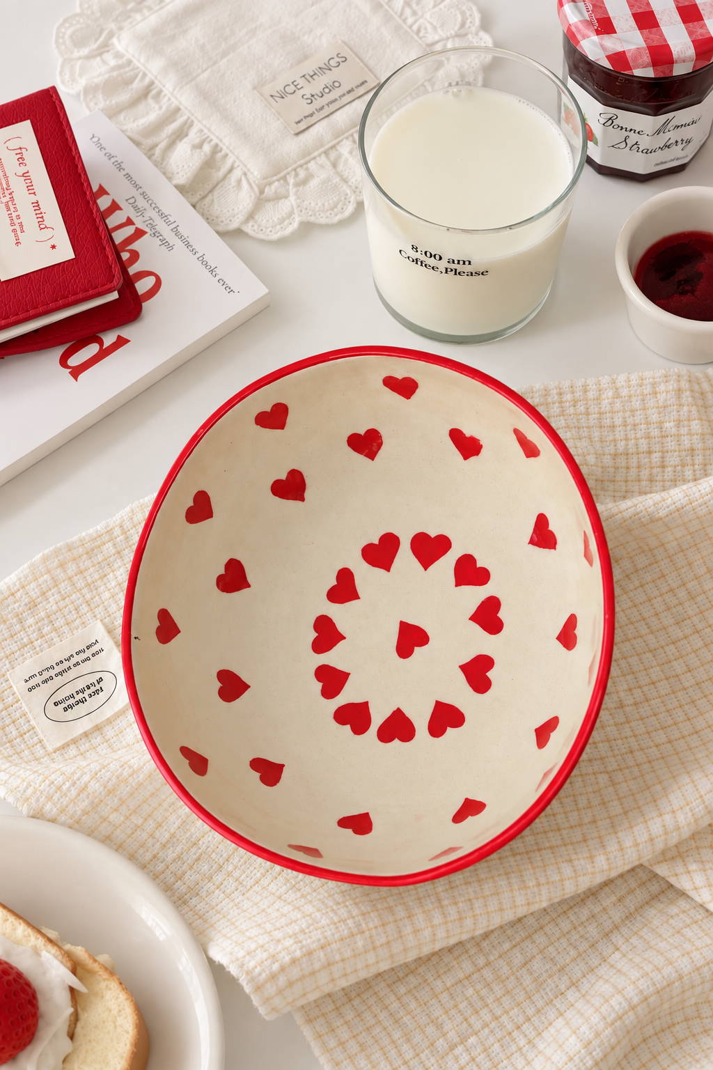A cream-colored ceramic bowl with a red rim and a pattern of small red hearts,