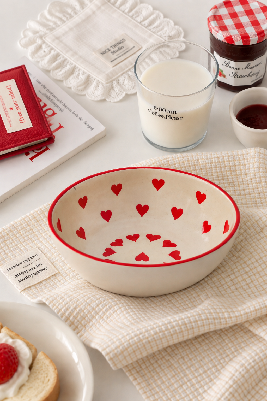 A cream-colored ceramic bowl with a red rim and red heart pattern