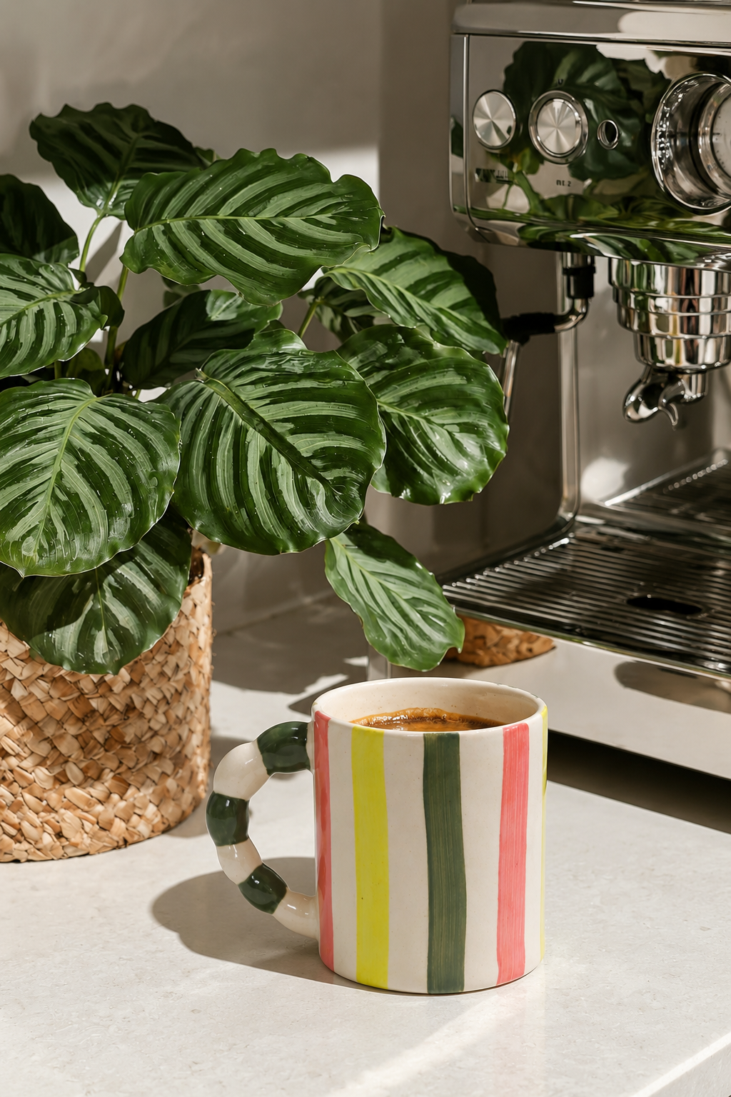 A ceramic coffee mug with vertical stripes in green, white, yellow, and pink strips