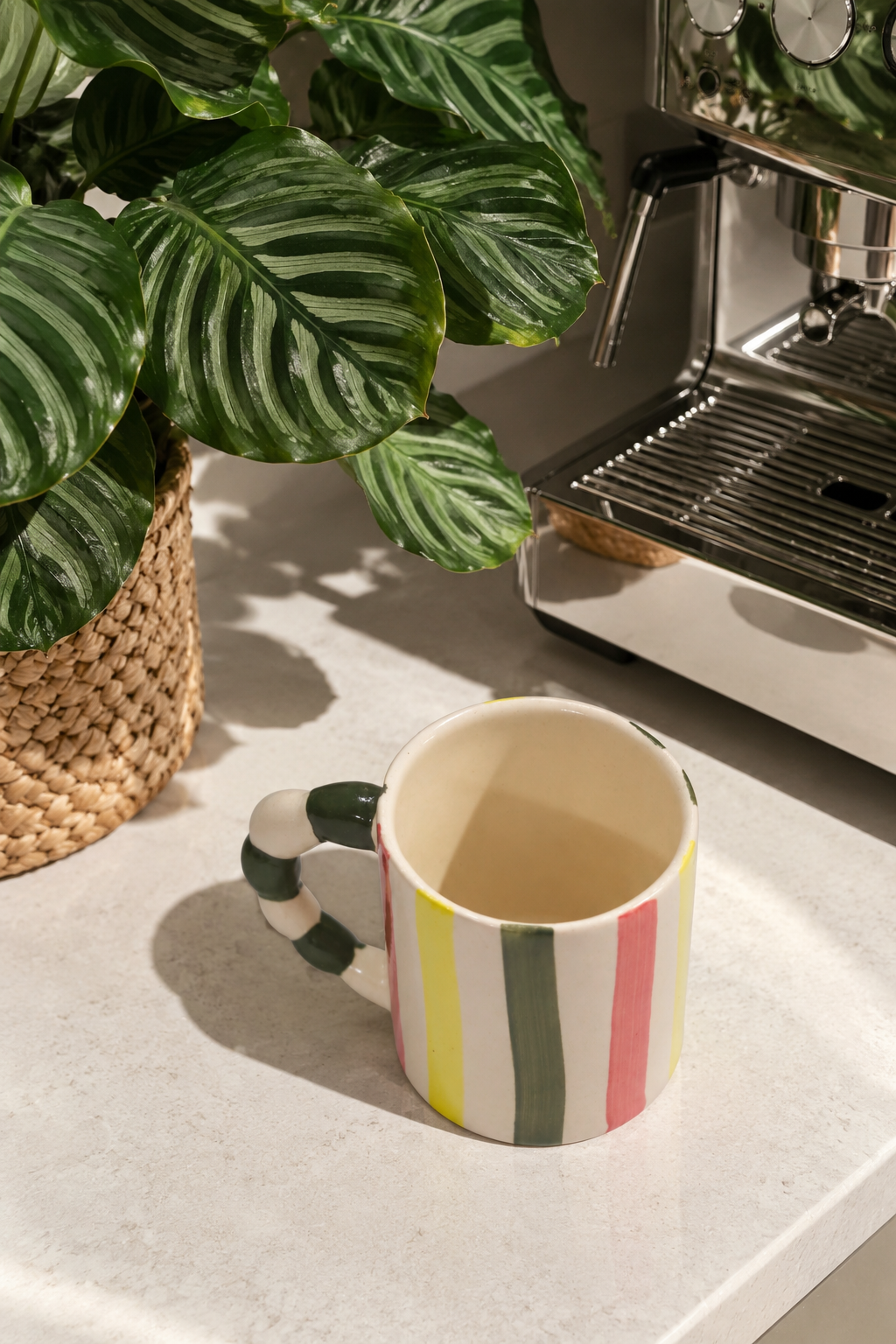 A ceramic coffee mug with vertical stripes in green, white, yellow, and pink
