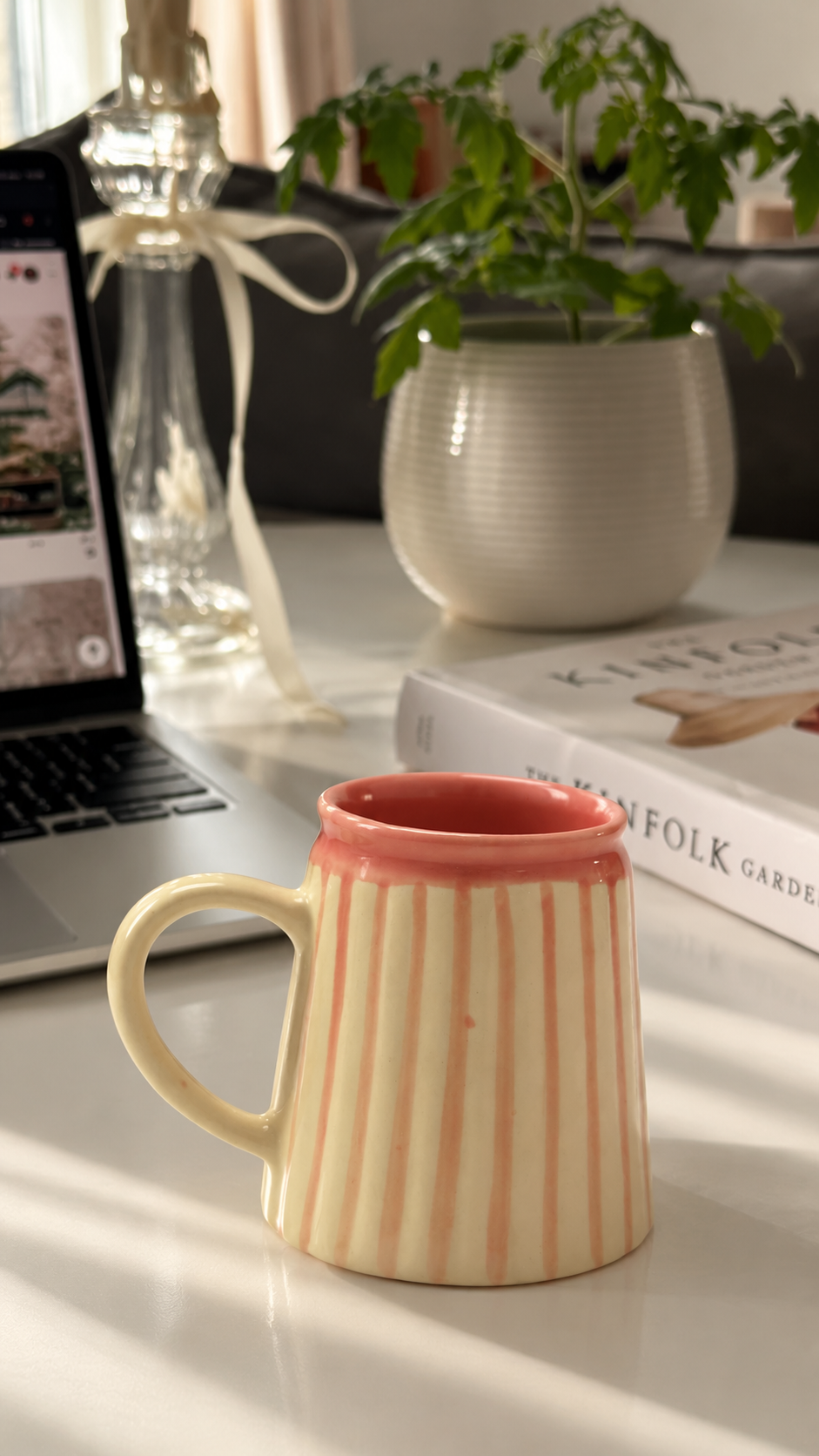 A ceramic mug with vertical pink and cream stripes