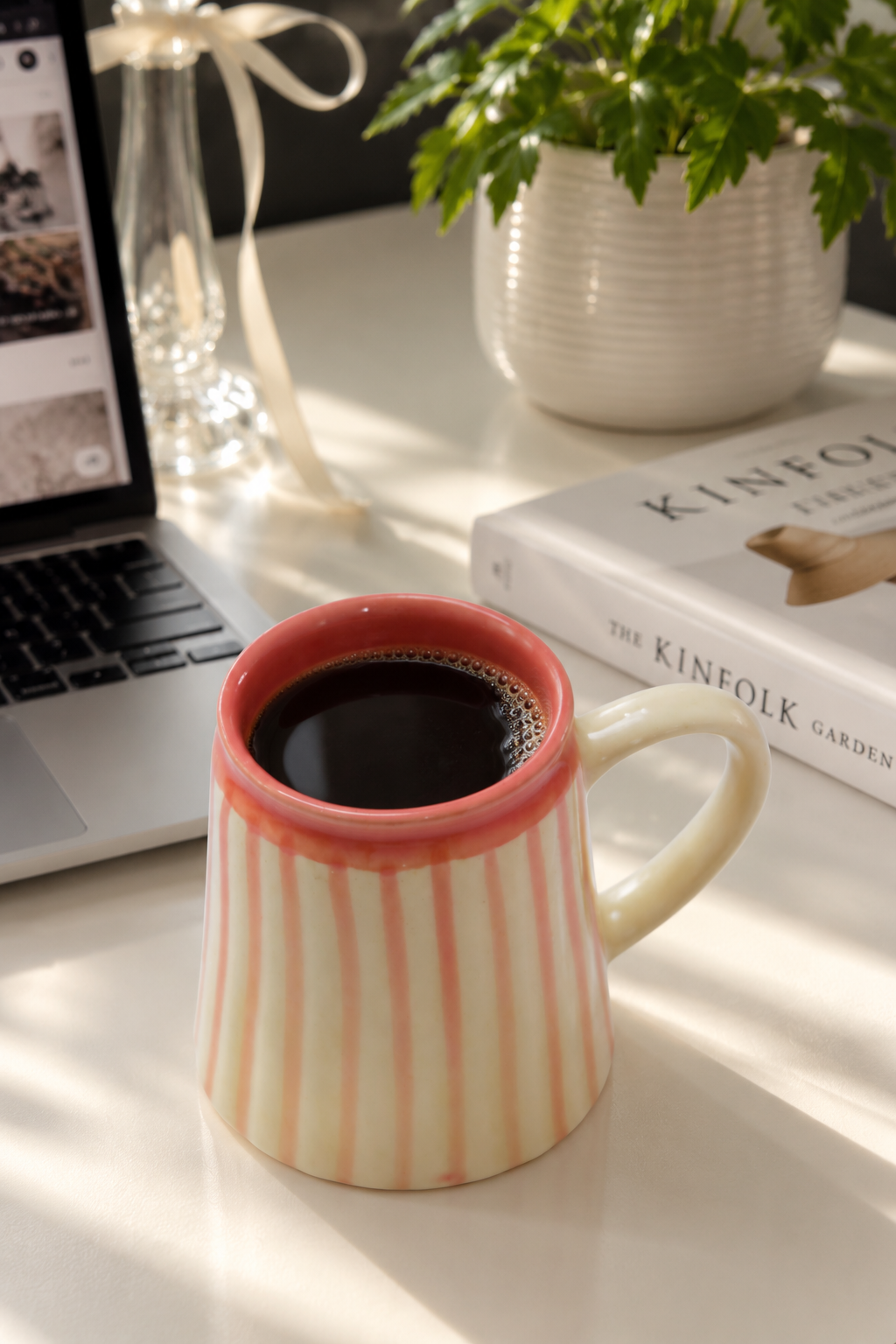 A ceramic mug with vertical pink stripes and a coral-pink rim