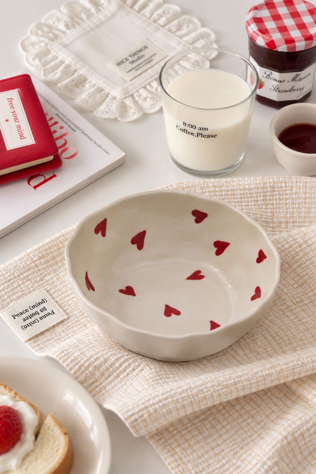 A ceramic bowl with a scalloped rim and small red hearts printed inside