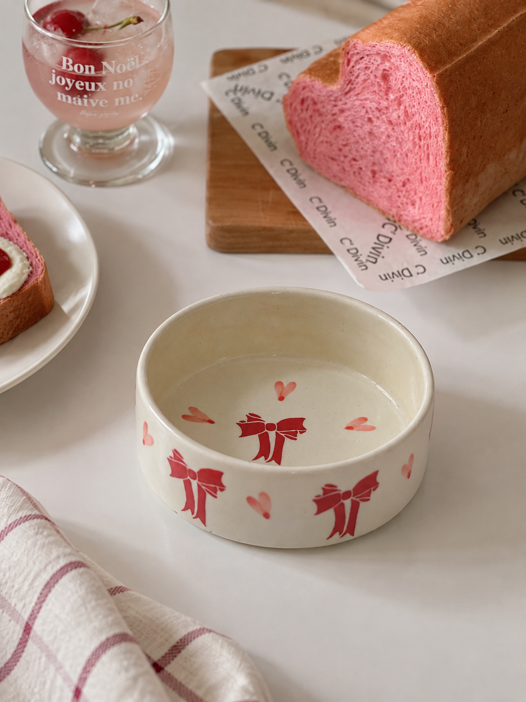 A cream-colored ceramic bowl decorated with red bows and hearts