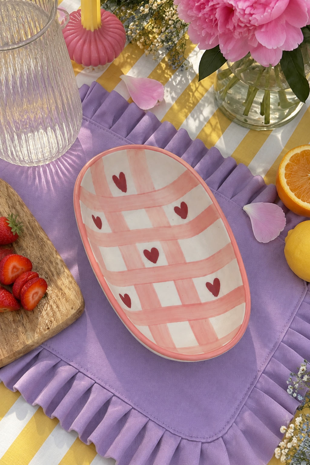 An oval ceramic serving bowl with a pink and white checkered pattern and small red hearts.