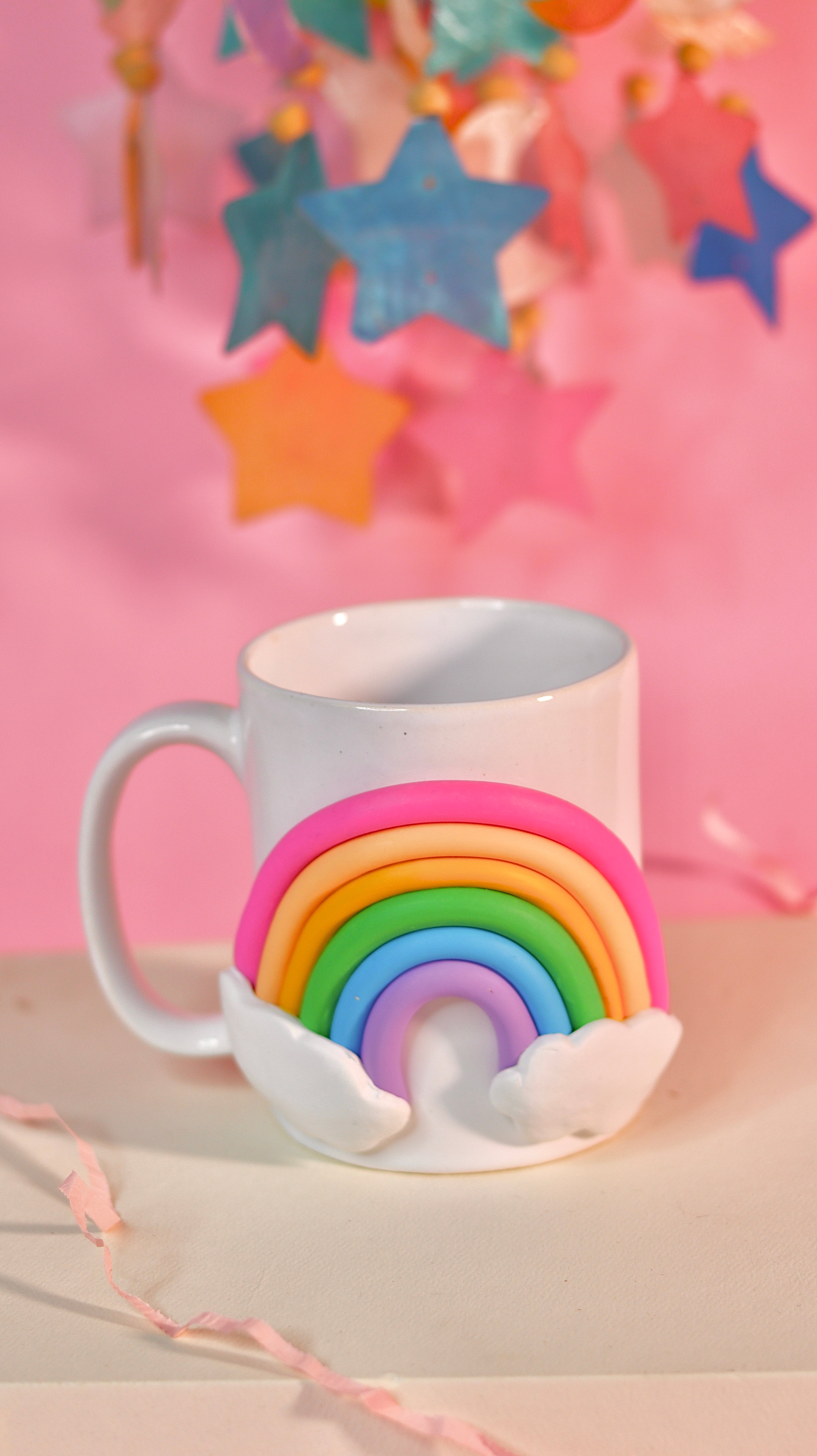 White mug with rainbow design on a pink background