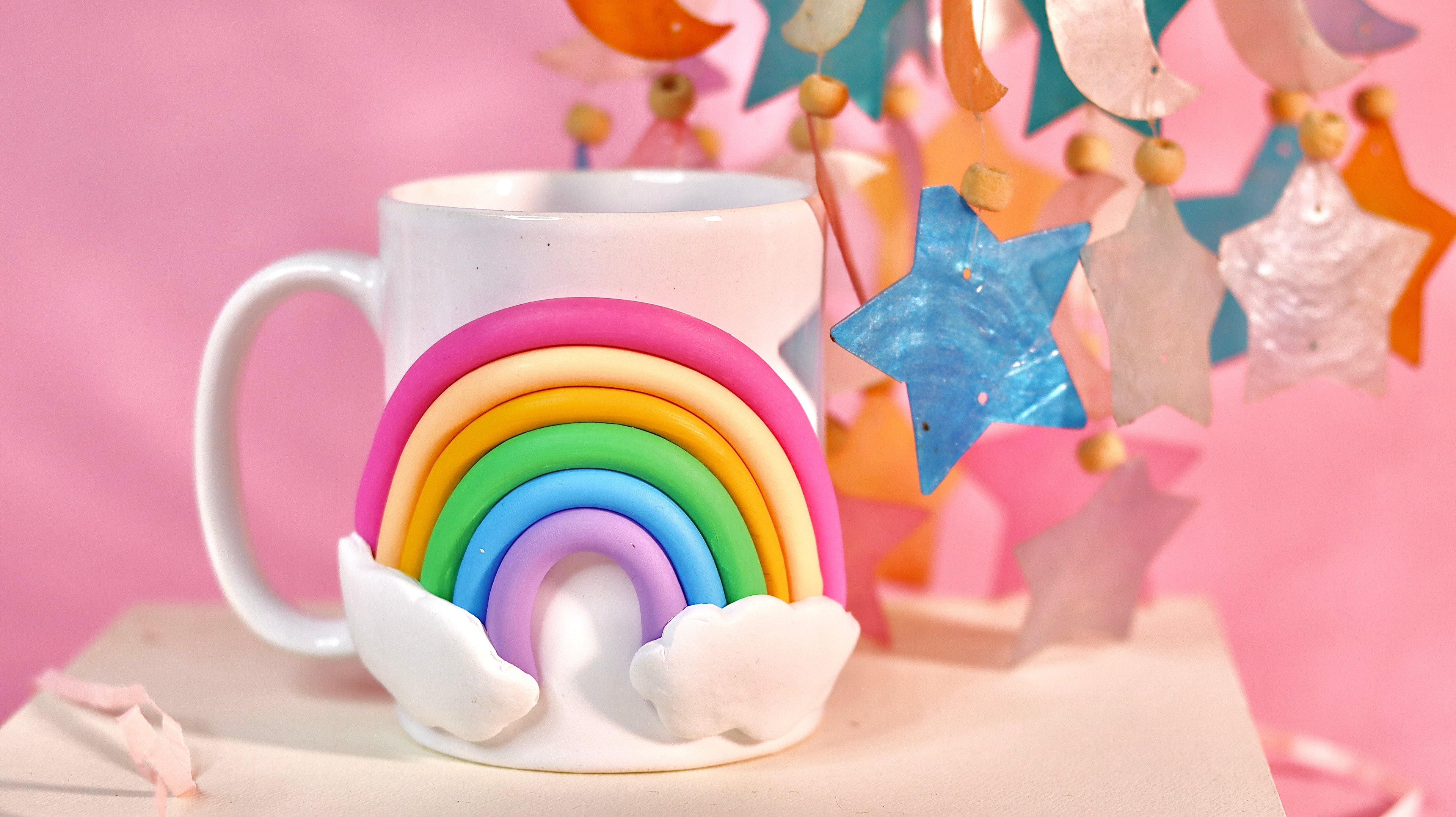 White mug with a rainbow design on a pink background